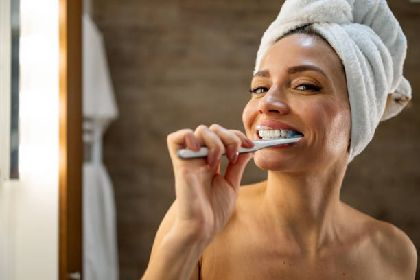 woman brushing her teeth after a shower
