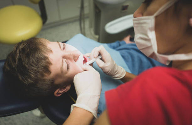 a child comfortably reclined in a dental chair during a dental procedure