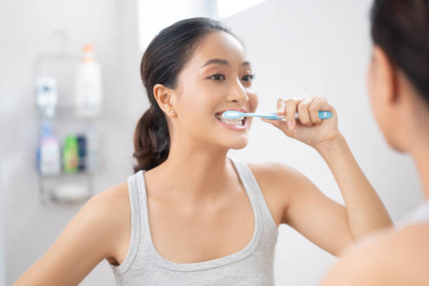 image of a woman brushing her teeth in front of a mirror