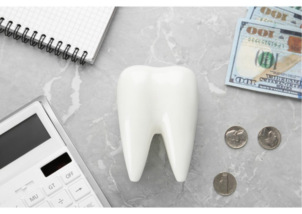 Tooth model beside calculator and cash representing the cost of dental implants and dental care expenses